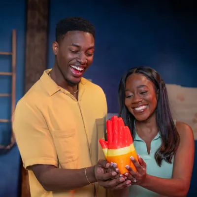 Couple smiles at wax hands they made together at Madame Tussauds Orlando.