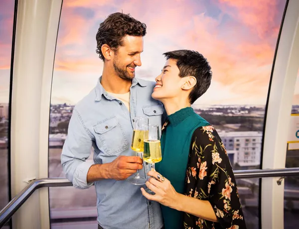 A couple shares a romantic moment with champagne, gazing into each other’s eyes inside an Orlando Eye capsule.