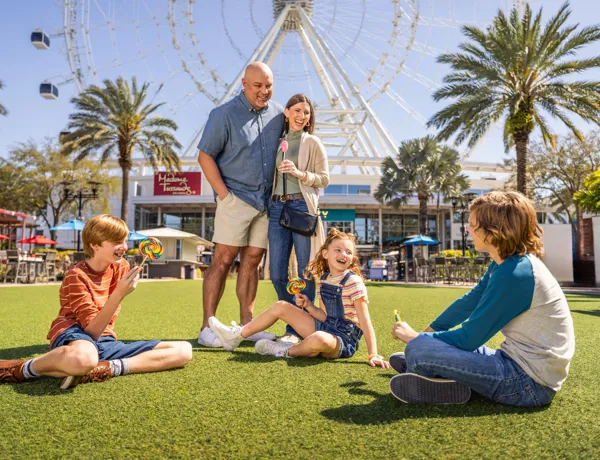 Happy family of five enjoys a sunny day at ICON Park Orlando, with treats and famous attractions behind them.